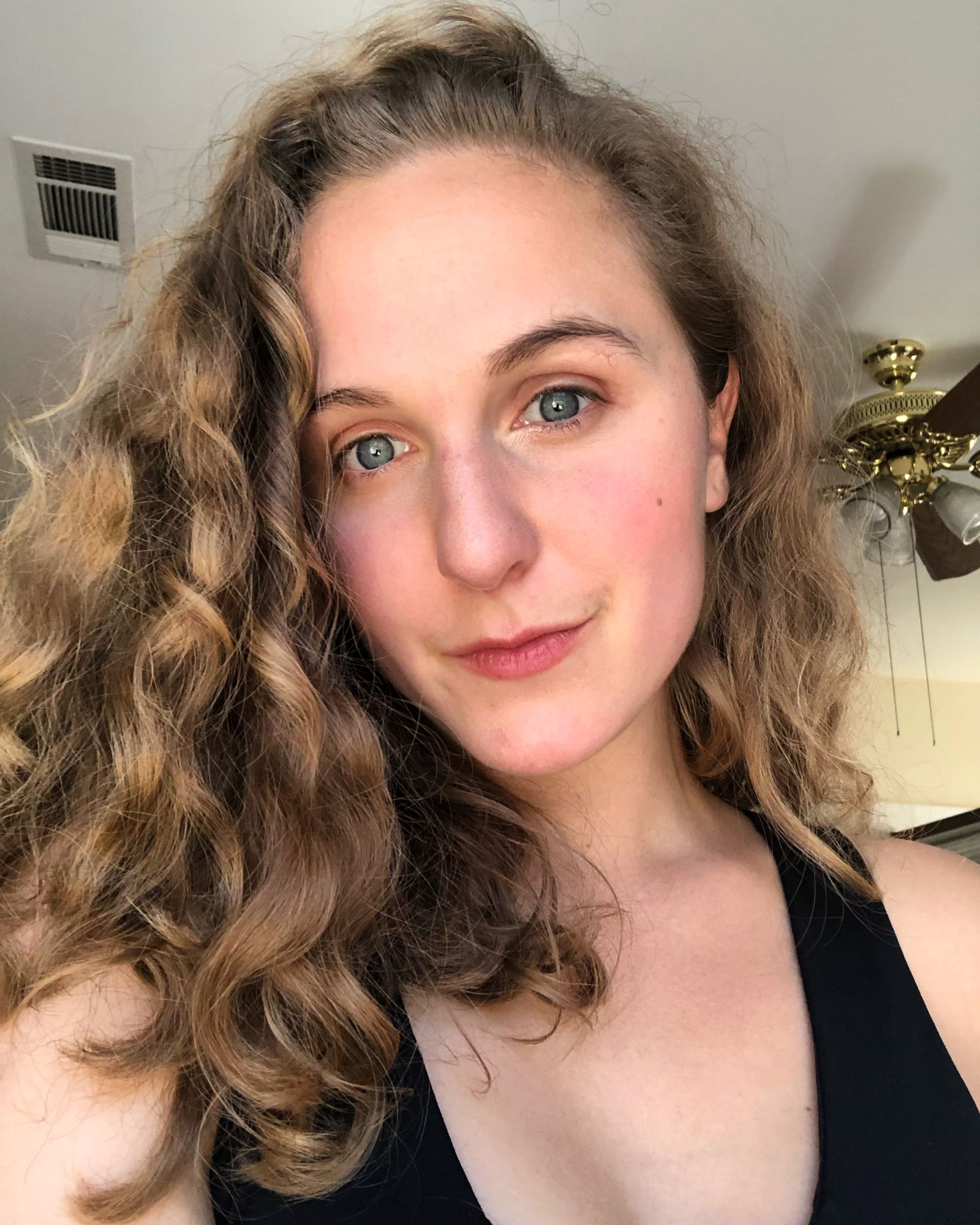 Hope with loose curls in a black top, half-smiling at the camera